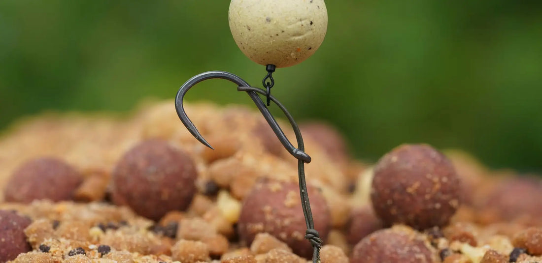 Multi rig black hook with twisted wire holding speckled bait ball on pellets