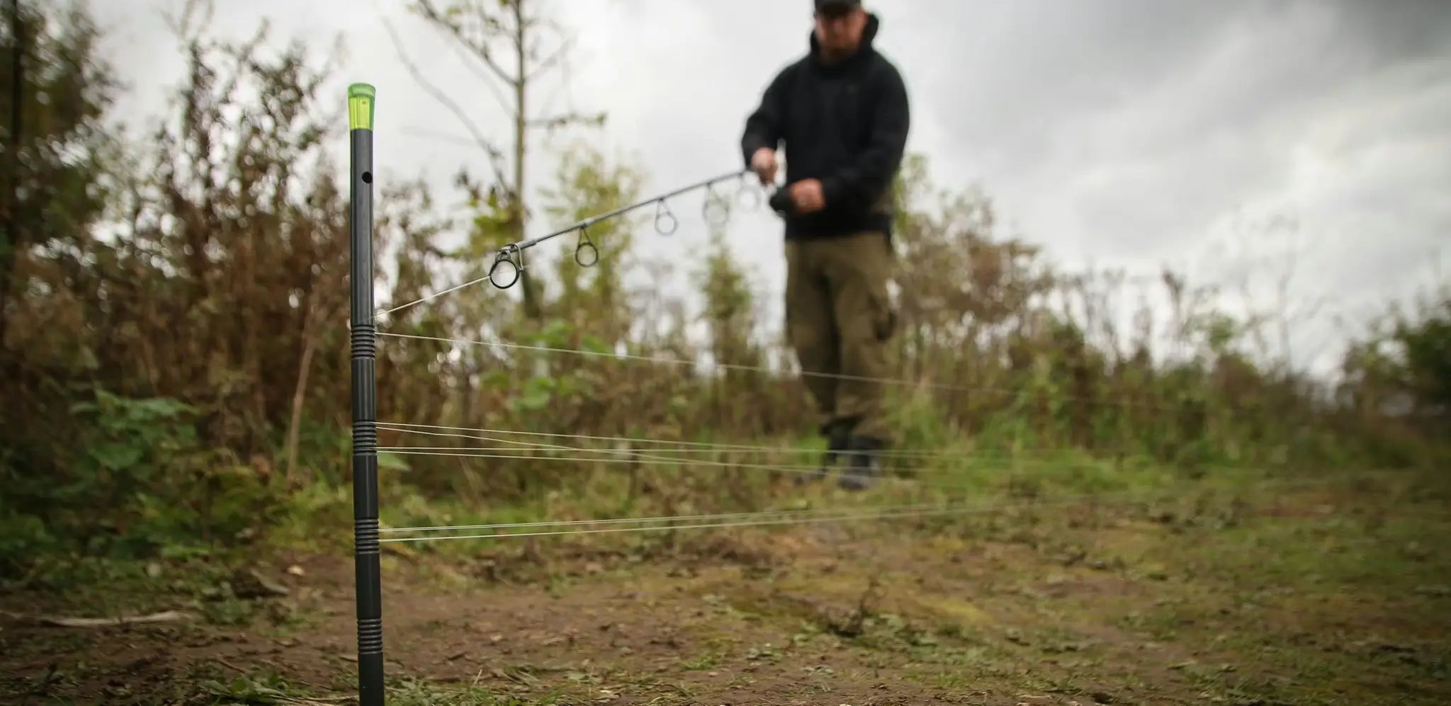 Black fishing rod with green tip and silver rings for distance sticks
