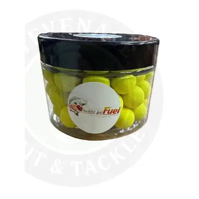 A clear plastic jar with a black lid contains bright yellow round carp fuel pop up pellets for fishing bait