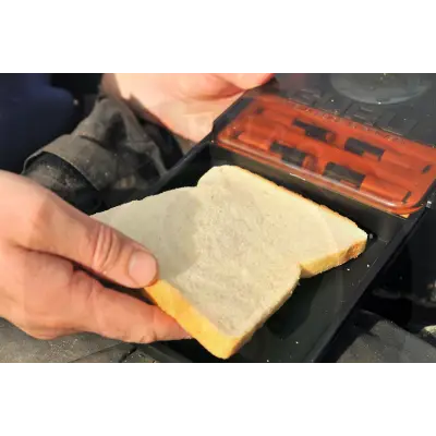 A slice of white bread held above an open black case of gardner tackle gpb polarised sunglasses packaging