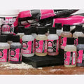 A collection of small transparent bottles with black caps and vibrant pink labels showing mainline carp response flavour mediterranean shellfish delivers