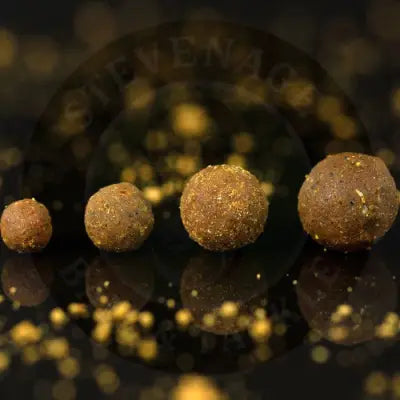 Four brown spherical krill active freezer fishing bait pellets with amino acids by stevenage bait on reflective surface