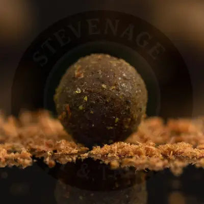 A dark brown spherical fishing bait ball with green and reddish flecks from sticky baits krill active freezer