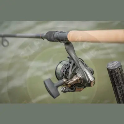 Black and bronze tackle guru a-class 4000 fishing reel with textured grip handle on wooden rod perfect reel option