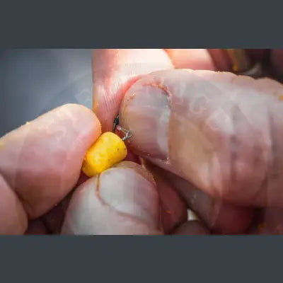 A small bright yellow fishing bait pellet held between fingers for Tackle Guru bait bayonets Stevenage bait use