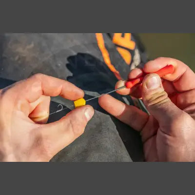 Yellow plastic tackle guru baiting needle with fine tapered point being adjusted using red-handled tool for stevenage bait