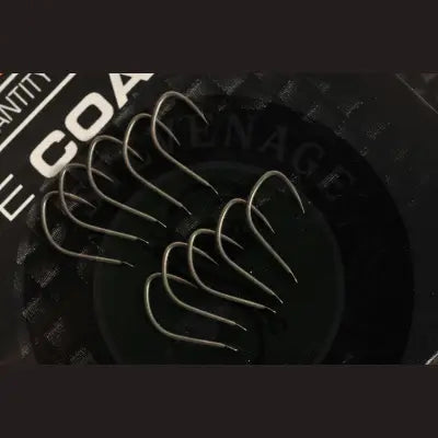 A set of sleek metallic guru f1 pellet barbless spade end fishing hooks ideal for targeting f1 carp with stevenage bait