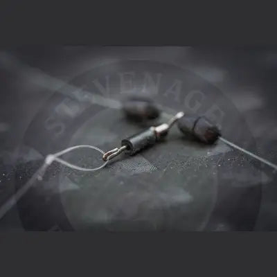 Black cylindrical fishing sinkers with metallic hooks attached to clear monofilament line in tackle guru heli swivel design