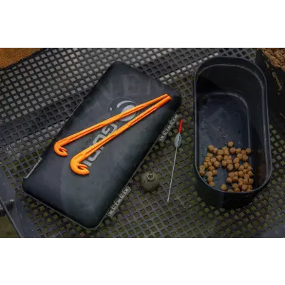 Black rectangular fishing tackle box with orange plastic hooks resting on top of tackle guru loop tyer for strong figure-of-eight loops