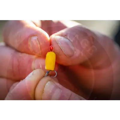 A bright yellow cylindrical micro hair stop with a red top and metal hook by tackle guru stevenage bait
