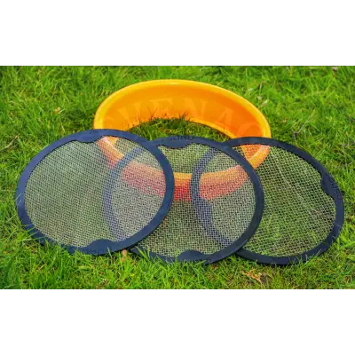 Three black-framed mesh guru multi riddle targets with fine grid pattern lying on grass near an orange bowl