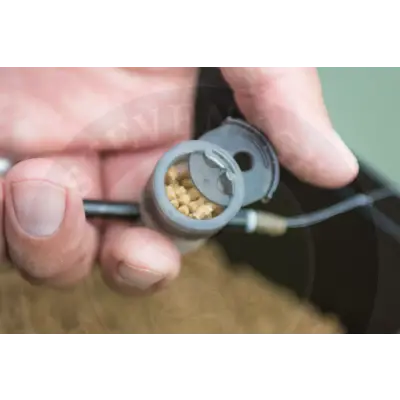 Gray plastic tackle guru pole pot bait dispenser with hinged lid filled with small yellowish stevenage bait pellets