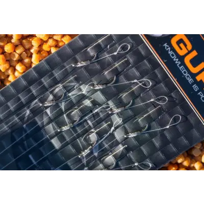 A set of silver-colored smwg standard fishing hooks with clear tips neatly arranged in a black tackle guru tray with orange branding
