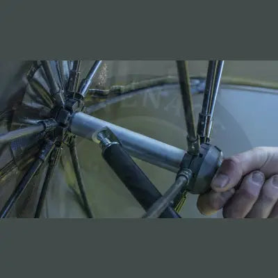 A hand adjusts a black and silver telescopic pole of the tackle guru umbrella large deluxe waterproof 210d canopy