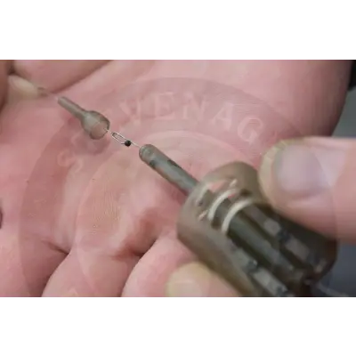 A metallic fishing lure with a segmented cylindrical body and hook featured with tackle guru x-safe spare tail rubbers