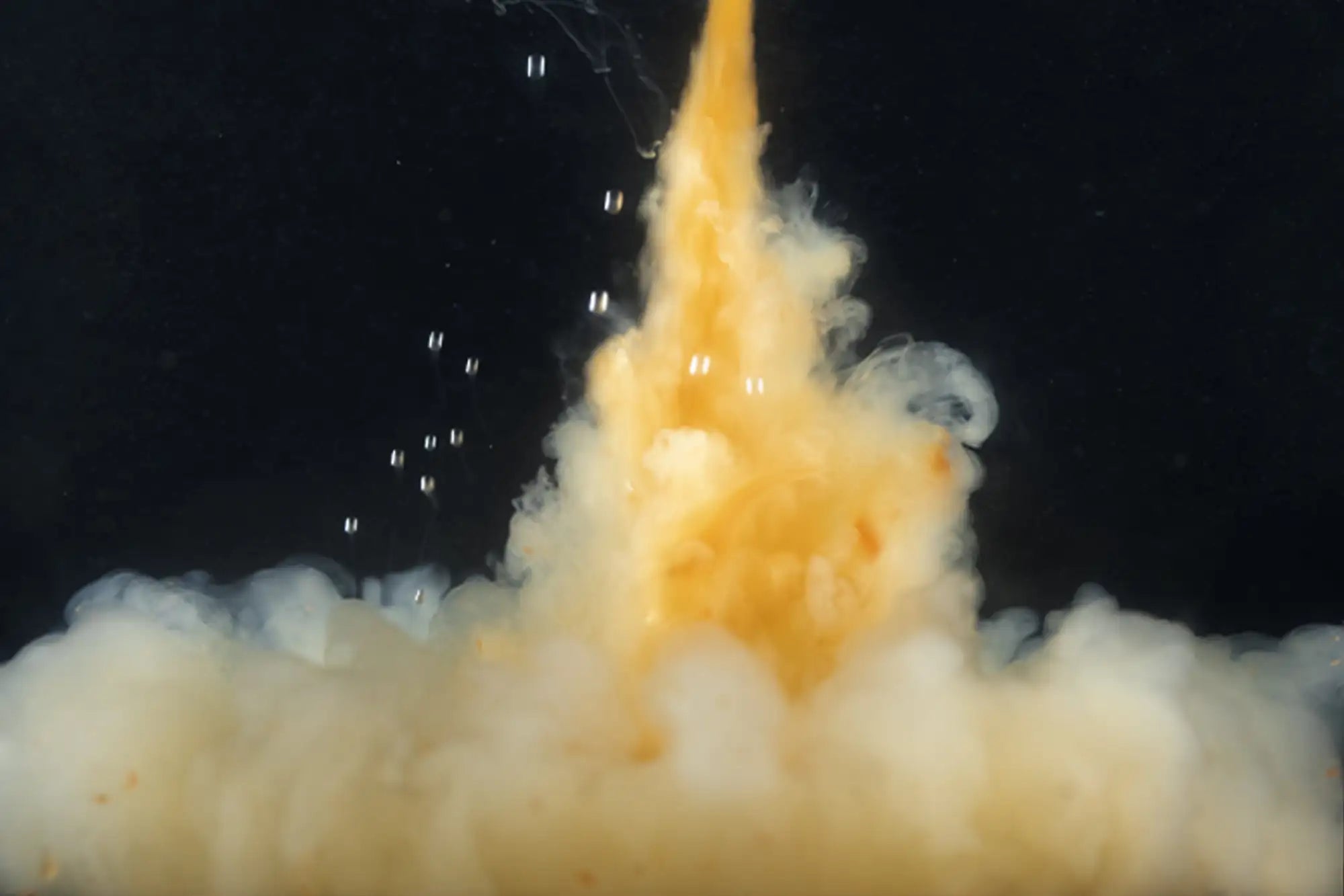 A vibrant orange and white liquid explosion against a black background.